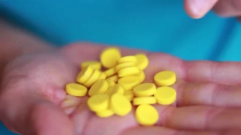 Yellow pills in the palm closeup 動画素材 80550060