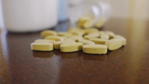 Yellow pills on the table, slowly approaching the bottle, focus on macro closeup Stock Footage 125637189