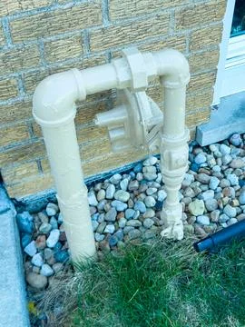 A yellow pipe structure is attached to a brick wall. It connects to other pip Fotos de archivo