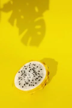 Yellow pitahaya dragon fruit in section white flesh with black seeds on yellow Stock Photos