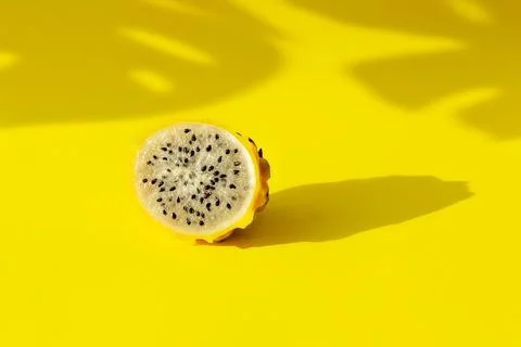 Yellow pitaya dragon fruit in section white flesh with black seeds on yellow Stock Photos