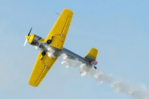 Yellow plane doing turns while sending smoke Stock Photos