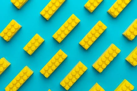 Yellow plastic building blocks background on turquoise blue Stock Photos