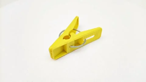 A yellow plastic clothes pin or clothes peg for isolated rotating on white Stock Footage 304688511