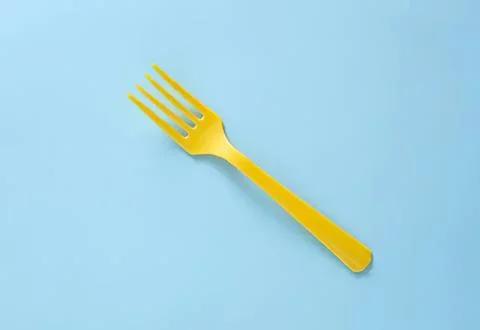 Yellow plastic fork on blue background Stock Photos