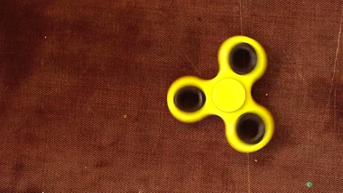 Yellow plastic spinner spinning on a wooden background. Slow motion. Stock Footage