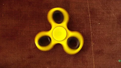 Yellow plastic spinner spinning on a wooden background. Slow motion. Stock Footage