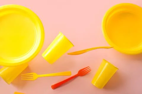 Yellow plastic tableware levitating on pink background Stock Photos