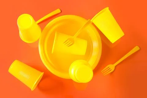 Yellow plastic tableware levitating on red background Stock Photos