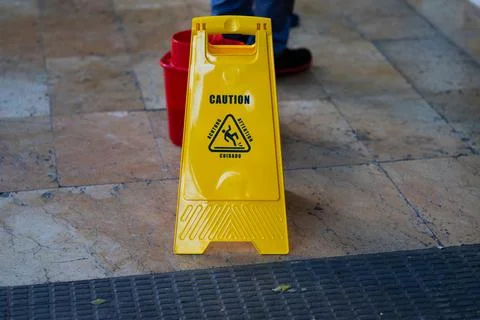 Yellow plastic wet floor caution sign in multiple languages Stock Photos