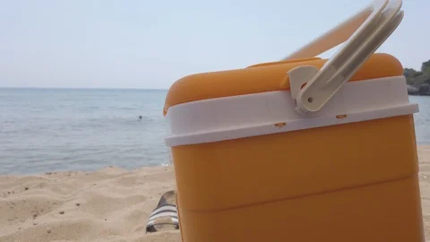 Yellow portable handheld mini fridge on beach in the background the sea Stock Footage 121874569
