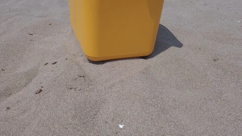 Yellow portable handheld mini fridge the side on sands beach Stock Footage 121887442