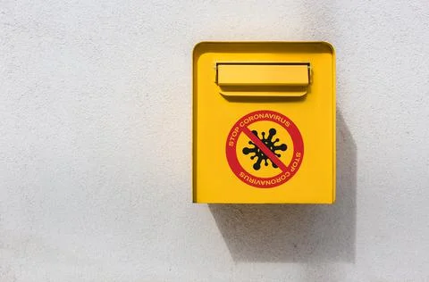 Yellow postbox on the wall with stop corona virus sign Stock Photos