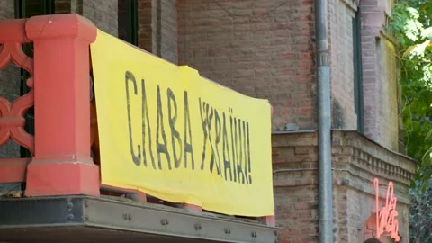 A yellow poster hangs on a stone balcony with the inscription glory to ukraine Video stock 216480671