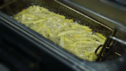 Yellow potatoes are deep-fried in a restaurant with boiling oil Stock Footage 141245961