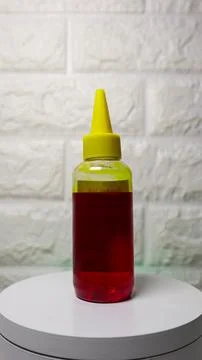 Yellow printer ink in a clear plastic bottle placed against a white backgro.. Foto stock