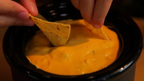 Yellow queso cheese dip in crock pot with chips being dipped Stock Footage 102138228