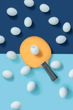 The yellow racket is in the middle of the table. There is a egg on the racket. Stock Photos