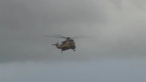 Yellow RAF helicopter flies through Welsh valley Stock Footage