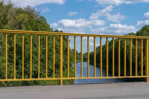 Yellow railing on a bridge of a river Stock Photos