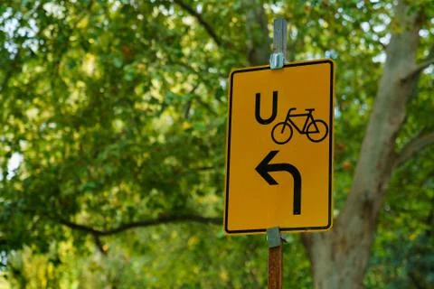 Yellow rectangular sign of the bike bypass road against the background of fol Stock Photos
