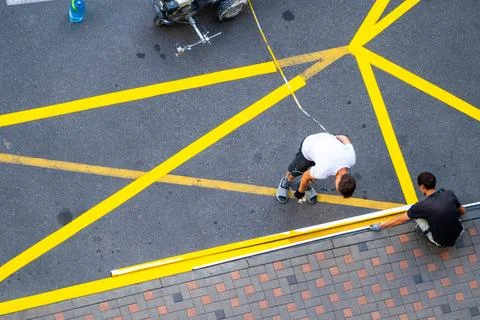 Yellow rectangular sign prohibiting parking on asphalt. Workers apply road .. Stock Photos