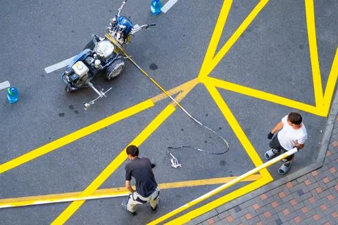 Yellow rectangular sign prohibiting parking on asphalt. Workers apply road Stock Photos