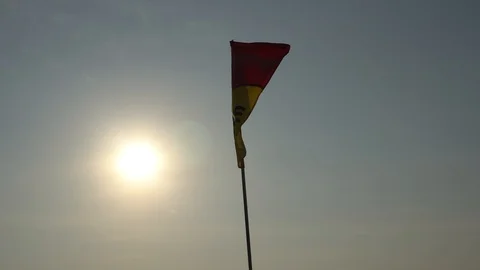 A yellow-red flag flutters in the wind. View of the bright sun. Video stock 106747081