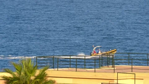A yellow-red motorboat with a canopy glides over mildly choppy sea waves. Stock Footage 248596038
