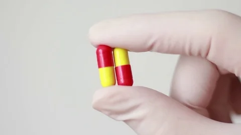Yellow-red pills in hand dressed in rubber glove Stock Footage 79589932