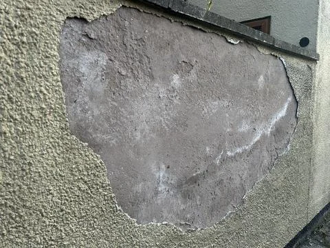 Yellow rendered wall with large area of broken render Stock Photos