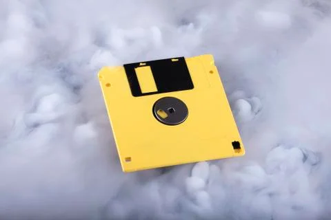 Yellow retro floppy disk in clouds. Information cloud conceptual image Stock Photos