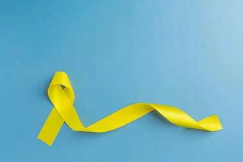 Yellow ribbon on colored background. Cancer concept.Suicide prevention day Stock Photos