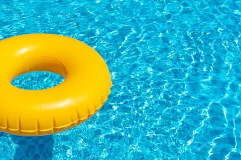 Yellow ring floating in refreshing blue swimming pool Stock Photos