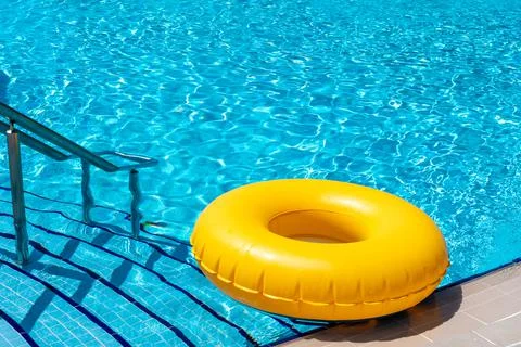 Yellow ring floating in refreshing blue swimming pool Stock Photos