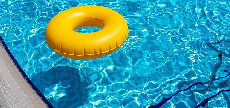 Yellow ring floating in refreshing blue swimming pool Stock Photos