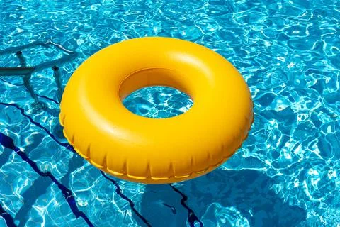 Yellow ring floating in refreshing blue swimming pool Stock Photos