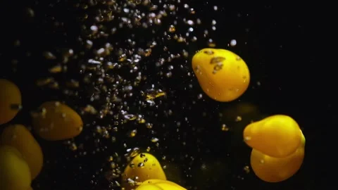 Yellow ripe cherry tomatoes falling in transparent water on black background. Stock Footage 249229049
