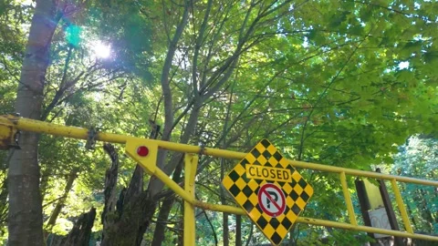 Yellow Road Closed and No Parking Sign on Metal Security Gate in Forest Stock Footage 345614789