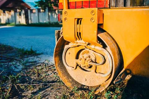 Yellow road roller resting on a patch of grass and dirt Stock Photos