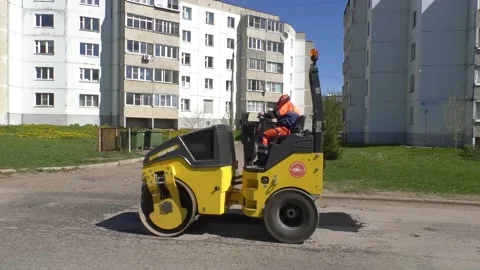 Yellow road roller rolls up a patch on the road Vídeos de archivo 153991998