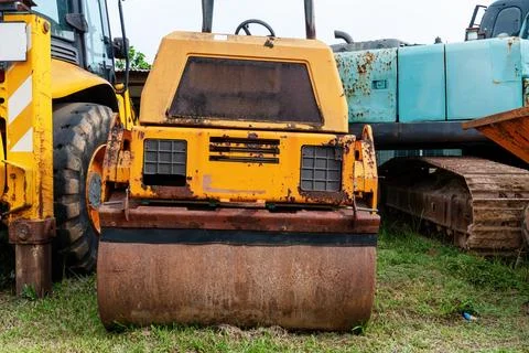 Yellow road roller with a rusty exterior stands on grass Stock Photos