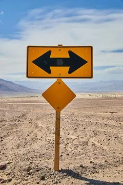Yellow road sign T intersection left or right in sandy desert Stock Photos
