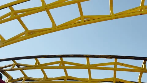 Yellow Roller Coaster Track Curves Under a Clear Sky in an Amusement Park Stock Footage 334513344