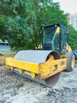 A yellow roller is parked at a construction site. The machine is designed for Stock Photos