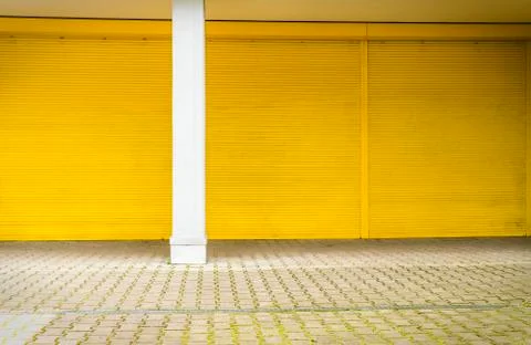 Yellow roller shutter and pavement for backgrounds and compositions Stock Photos