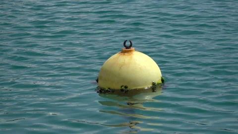 A yellow, round buoy floating on the surface of undulating water. Video stock 106623625