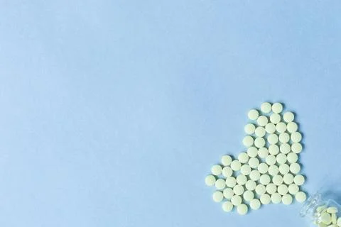 Yellow round tablets lie in the shape of a heart poured out of a glass bottle Stock Photos