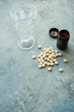Yellow round tablets pills vitamins, plastic bottle and glass cup Stock Photos