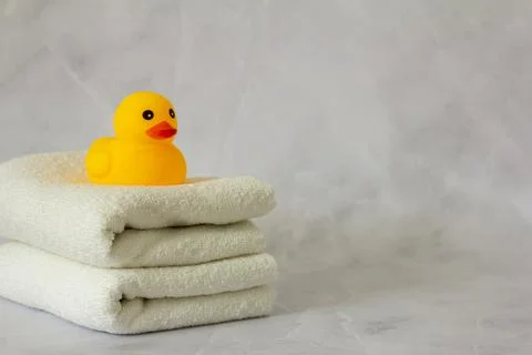 A yellow rubber duck for bathing on a stack of clean white towels. Stock Photos
